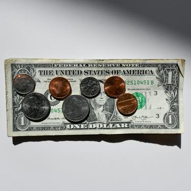 Photo of U.S. dollar bill with coins on top of it.